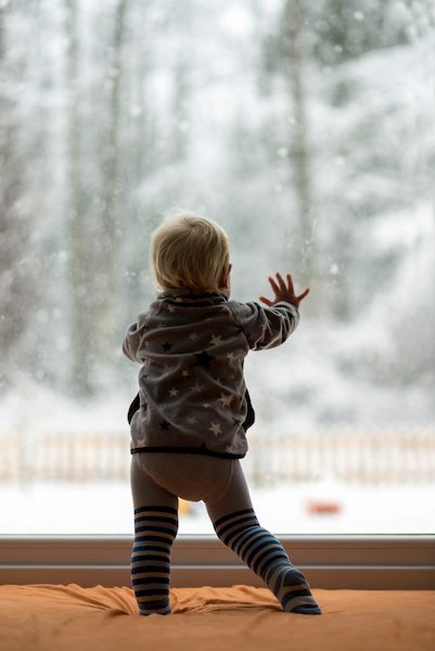 A small child standing at the window excited for christmas